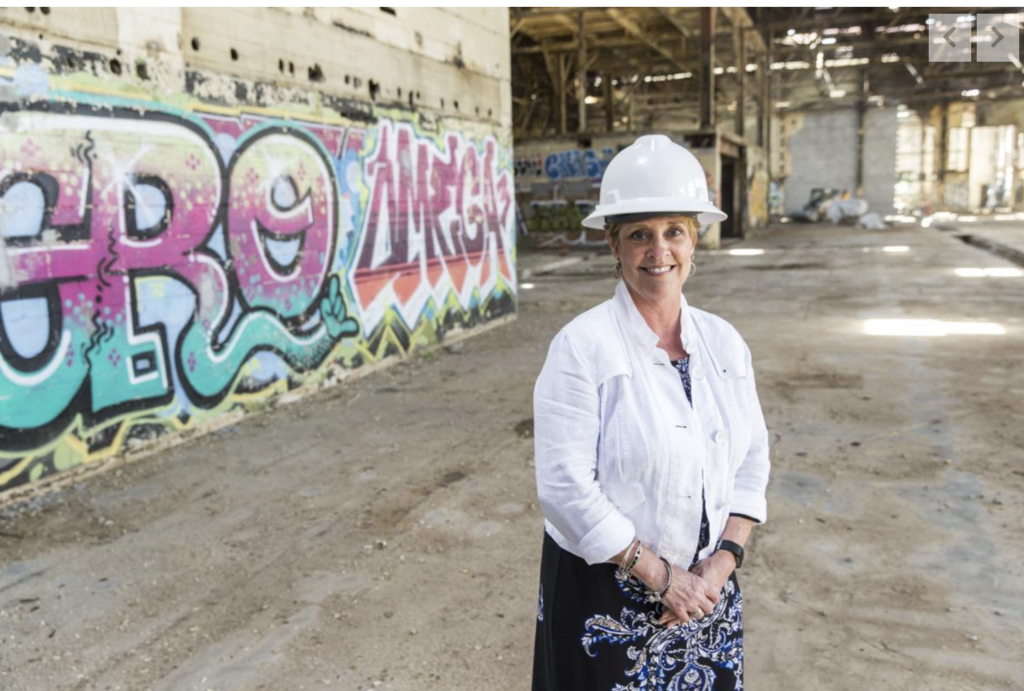 woman in hard hat by graffitied wall